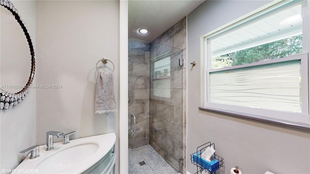 bathroom featuring a shower with door and vanity