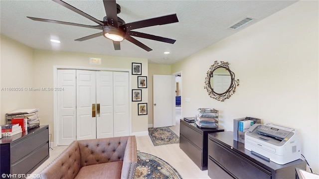 home office with light wood-type flooring, a textured ceiling, and ceiling fan