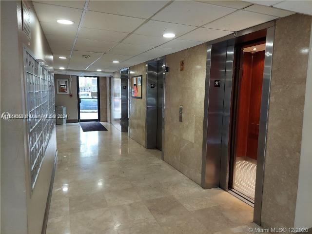 corridor featuring a drop ceiling and elevator