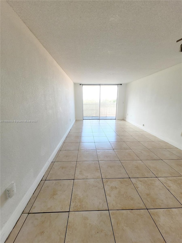 spare room with a textured ceiling, light tile patterned floors, and expansive windows