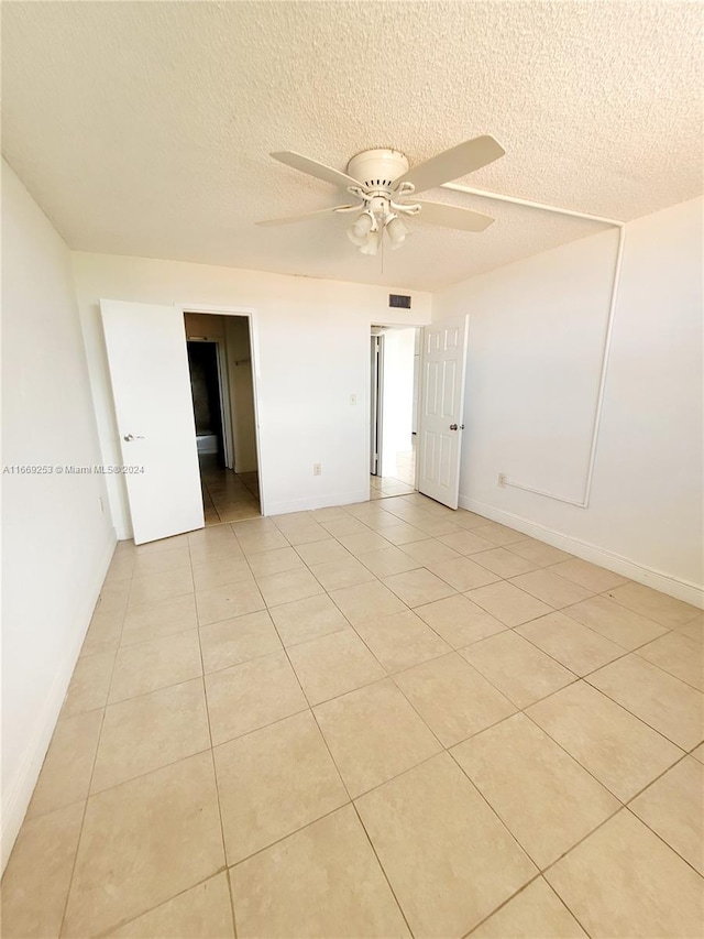 unfurnished room with ceiling fan, a textured ceiling, and light tile patterned floors