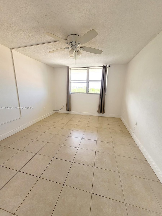 spare room featuring a textured ceiling, light tile patterned floors, and ceiling fan