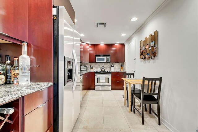 kitchen featuring light stone counters, light tile patterned floors, ornamental molding, backsplash, and appliances with stainless steel finishes