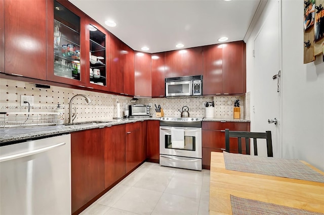 kitchen featuring light stone counters, light tile patterned floors, sink, appliances with stainless steel finishes, and decorative backsplash