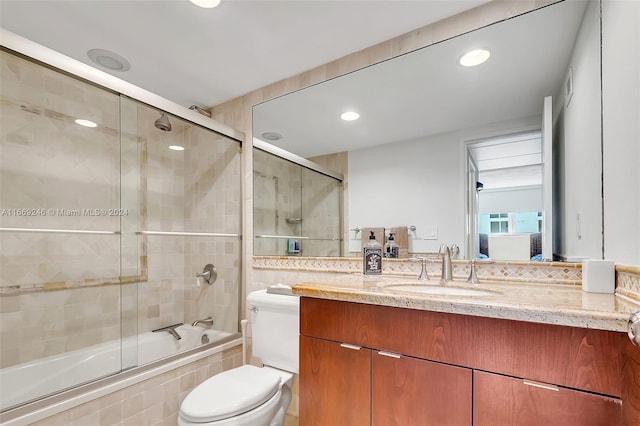 full bathroom with toilet, vanity, and bath / shower combo with glass door