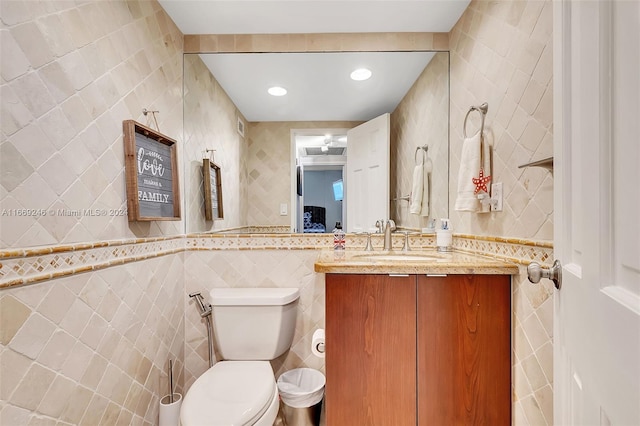 bathroom featuring tile walls, vanity, and toilet