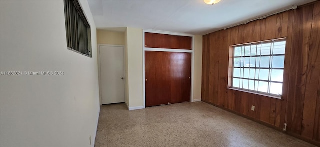 unfurnished bedroom with a closet and wood walls