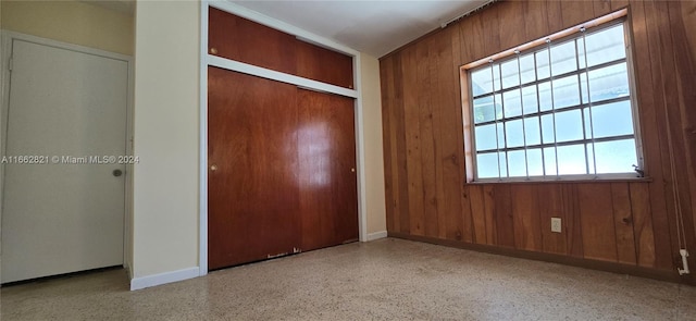 unfurnished bedroom with wood walls and a closet