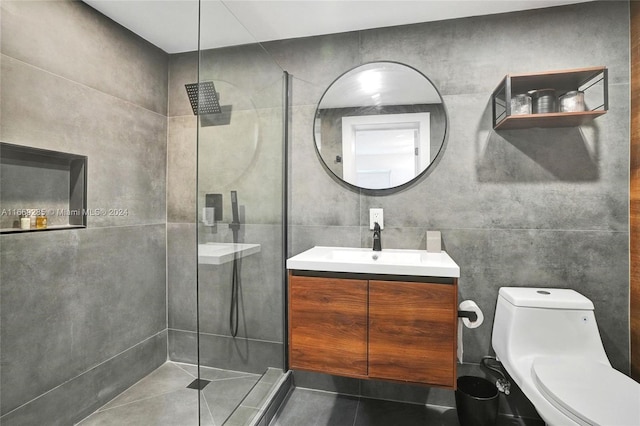 bathroom featuring tile walls, tiled shower, vanity, tile patterned flooring, and toilet