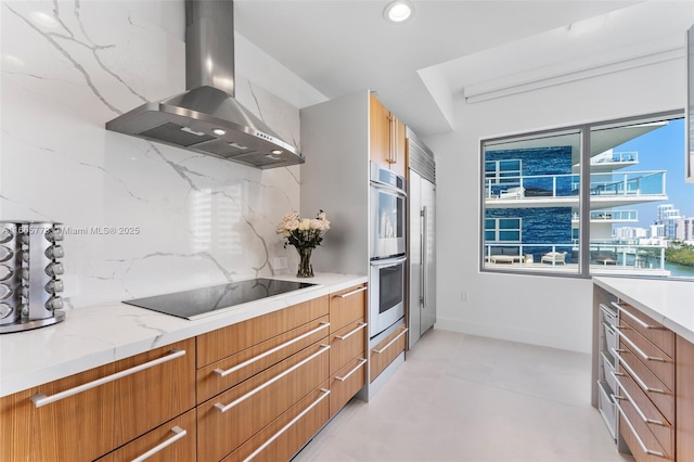 kitchen with stainless steel appliances, island exhaust hood, light stone countertops, and backsplash