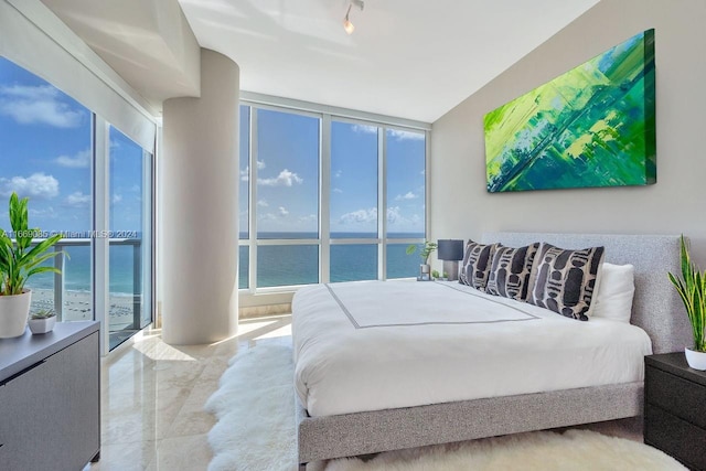 bedroom featuring a wall of windows, a water view, and access to exterior