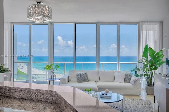 living room featuring a notable chandelier, a water view, and a beach view