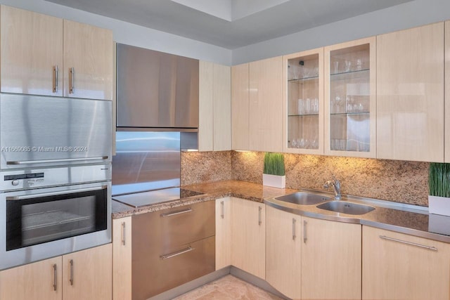 kitchen with electric cooktop, light brown cabinets, stainless steel oven, and sink