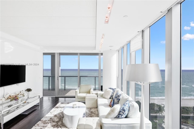 living room with a water view, floor to ceiling windows, and dark wood-type flooring