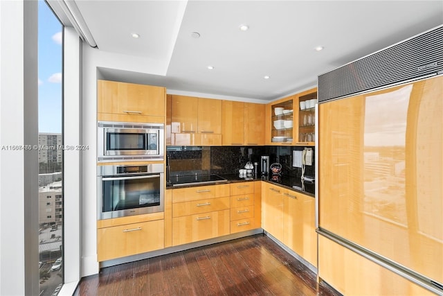 kitchen featuring dark wood-type flooring, light brown cabinetry, built in appliances, and tasteful backsplash