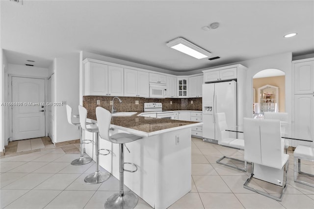 kitchen with white cabinetry, a breakfast bar, tasteful backsplash, white appliances, and sink