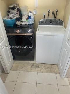 clothes washing area with light tile patterned floors and washer and dryer