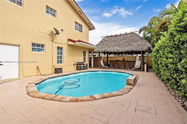 view of swimming pool featuring a patio, a bar, and cooling unit