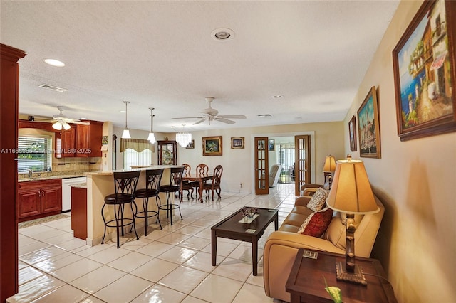 living room with ceiling fan, french doors, light tile patterned flooring, and a textured ceiling