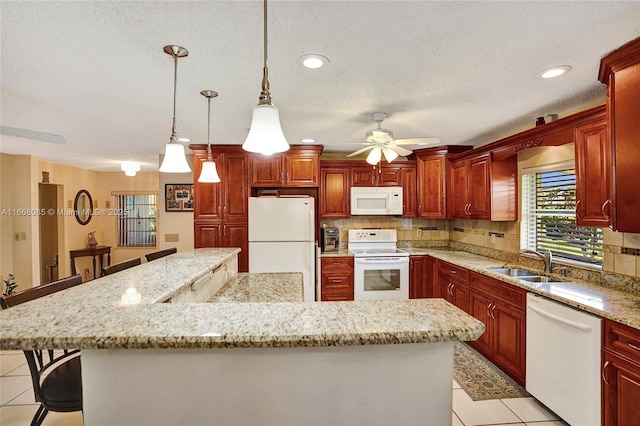 kitchen featuring a breakfast bar, white appliances, sink, ceiling fan, and decorative light fixtures