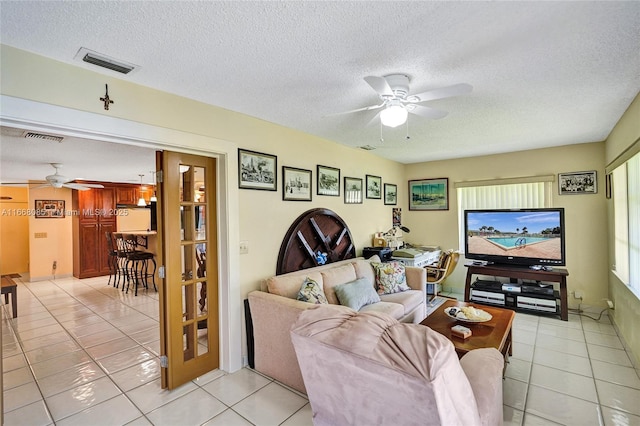 tiled living room featuring ceiling fan, a healthy amount of sunlight, and a textured ceiling