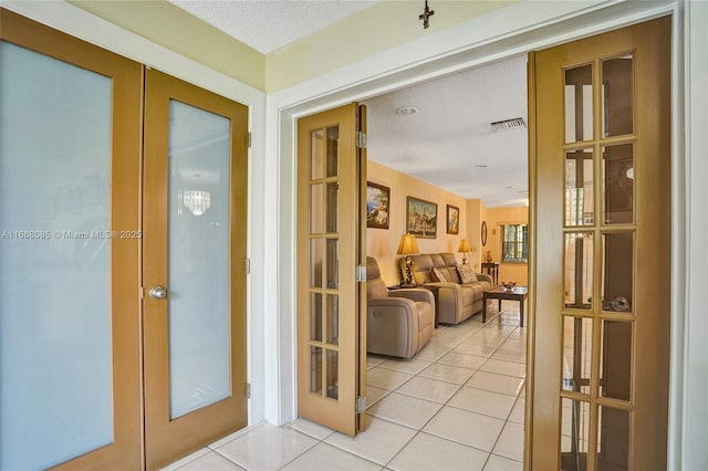 hallway with french doors, light tile patterned flooring, and a textured ceiling