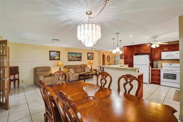 dining area featuring ceiling fan with notable chandelier, a textured ceiling, and light tile patterned flooring