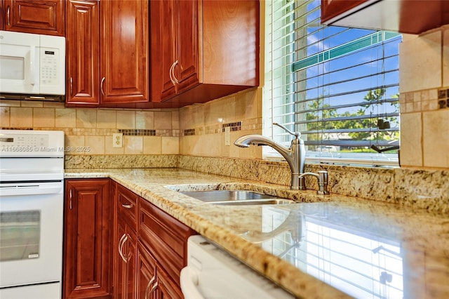 kitchen with white appliances, light stone countertops, sink, and decorative backsplash