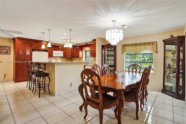 dining area with a textured ceiling, light tile patterned floors, and ceiling fan with notable chandelier