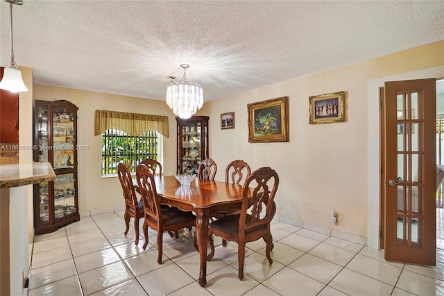 dining space featuring a chandelier, light tile patterned floors, and a textured ceiling