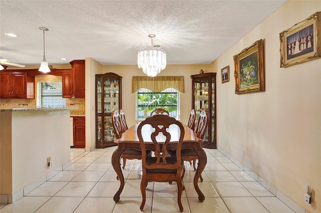 tiled dining area with ceiling fan with notable chandelier and a textured ceiling