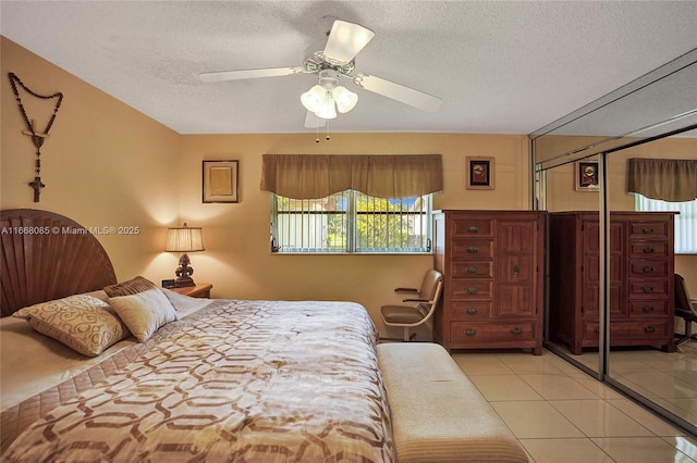 bedroom with light tile patterned floors, a textured ceiling, a closet, and ceiling fan