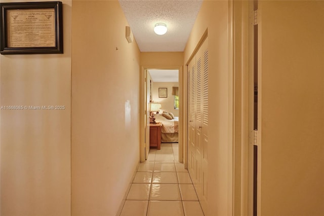 hall with a textured ceiling and light tile patterned floors