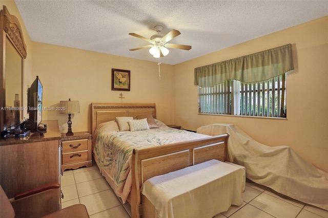 bedroom with ceiling fan, light tile patterned floors, and a textured ceiling