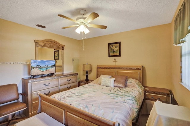 bedroom with ceiling fan and a textured ceiling