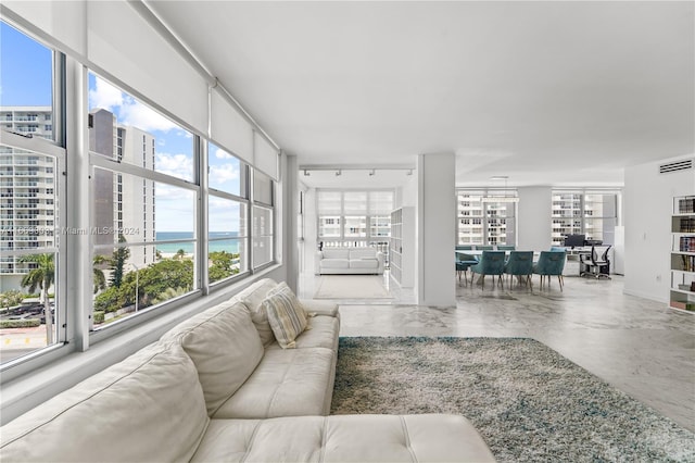 living room featuring a healthy amount of sunlight, a water view, and concrete floors