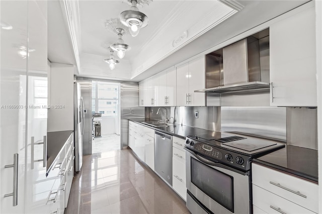 kitchen with tile patterned flooring, sink, white cabinetry, wall chimney range hood, and stainless steel appliances