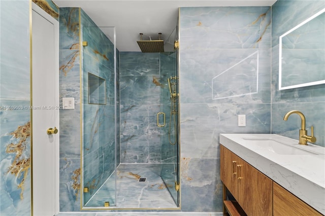 bathroom with tile walls, a shower with shower door, and vanity