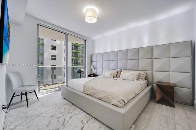 bedroom featuring a wall of windows and light hardwood / wood-style floors