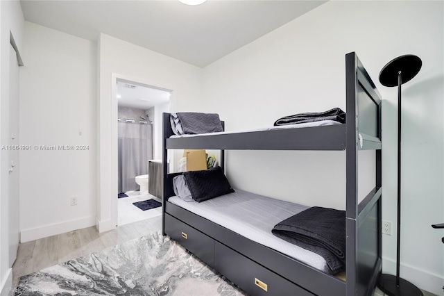 bedroom featuring connected bathroom and light hardwood / wood-style floors