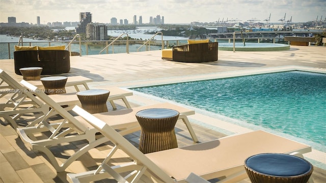 pool with a patio, a water view, and a city view