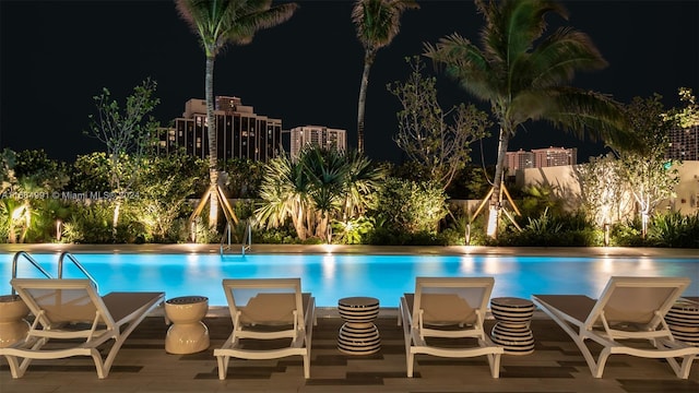 pool at night featuring a patio area