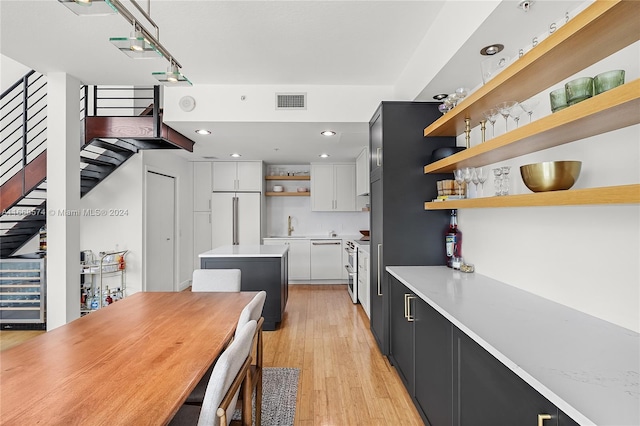 kitchen featuring white cabinets, stainless steel range with electric stovetop, light wood-type flooring, and high end fridge