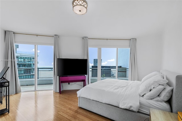 bedroom featuring access to outside, hardwood / wood-style flooring, and multiple windows