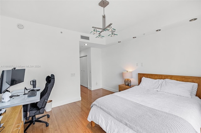 bedroom with wood-type flooring and an inviting chandelier