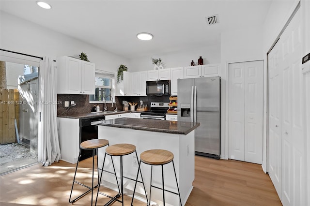 kitchen with plenty of natural light, white cabinets, black appliances, and a kitchen island