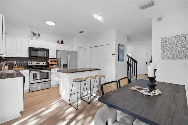 kitchen featuring dark countertops, stainless steel appliances, and white cabinetry