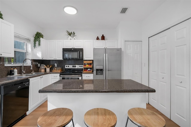 kitchen featuring black appliances, white cabinetry, a center island, and tasteful backsplash