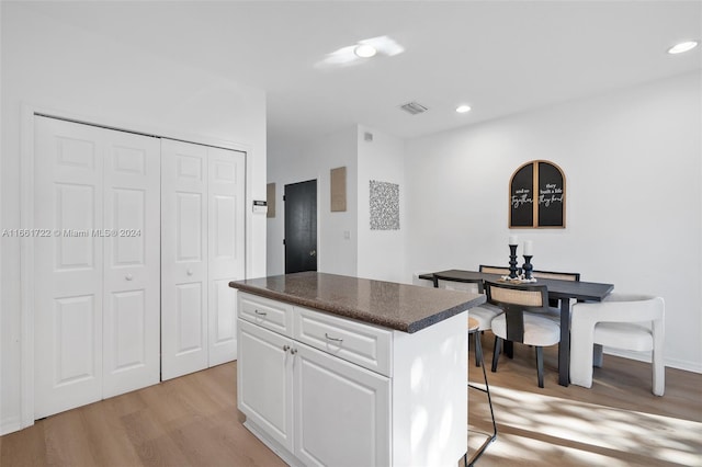 kitchen with a kitchen bar, a kitchen island, light hardwood / wood-style flooring, and white cabinetry