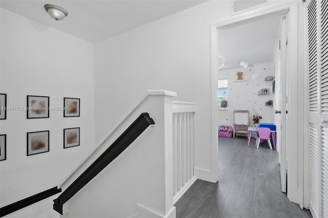 corridor with baseboards, visible vents, wood finished floors, and an upstairs landing